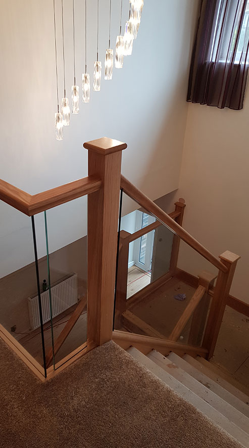 A seamless oak & glass staircase taken from the landing looking down